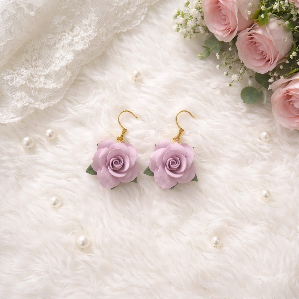 Hand-sculpted lavender purple polymer clay rose earrings on gold hooks, styled with white lace, pearls, and fresh pink roses.